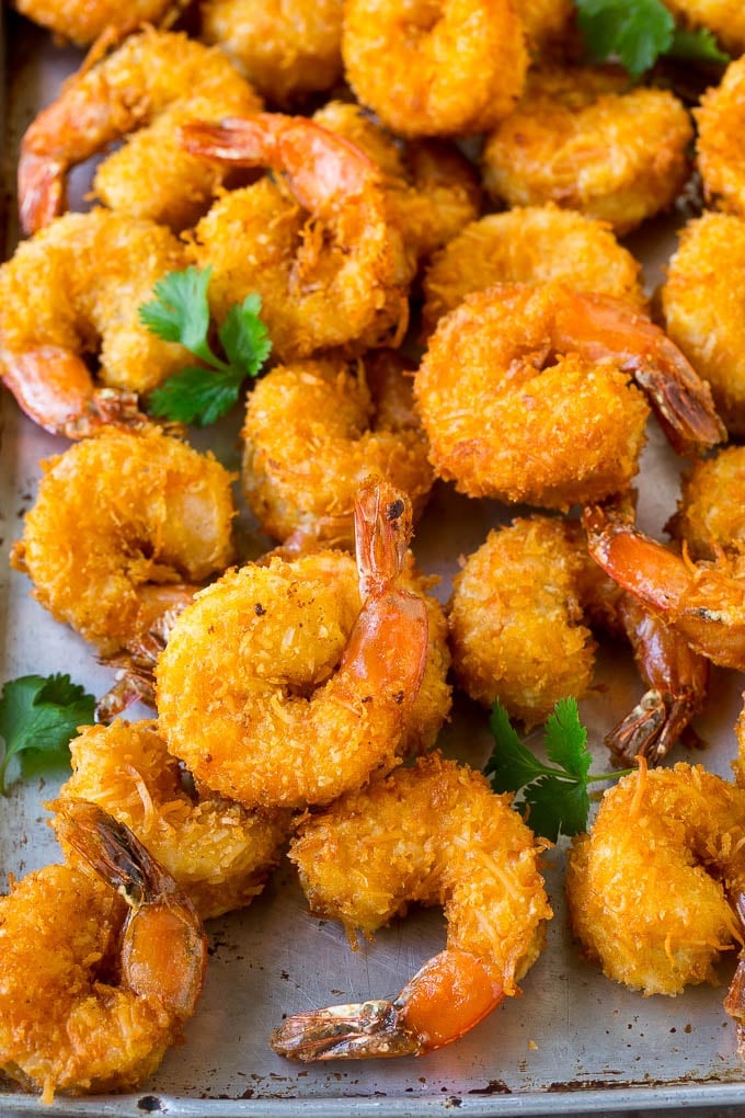 Coconut Shrimp Recipe | Fried Shrimp | Shrimp Appetizer #shrimp #coconut #appetizer #seafood #dinner #sadud A pile of crispy coconut shrimp on a sheet pan with cilantro leaves for garnish.