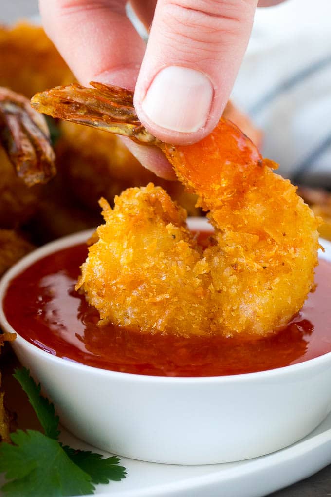 Coconut Shrimp Recipe | Fried Shrimp | Shrimp Appetizer #shrimp #coconut #appetizer #seafood #dinner #sadud A hand dipping a crispy prawn into a bowl of sweet chili sauce.