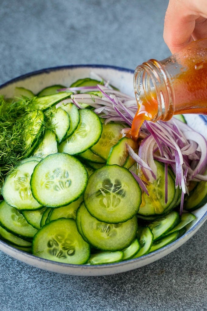 Cucumber Salad Recipe | Cucumber Dill Salad | Cucumber Recipe #cucumbers #salad #glutenfree #sidedish #sadud Dressing being poured over sliced vegetables and fresh dill.