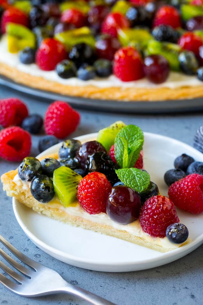 Fruit Pizza Recipe | Dessert Pizza | Fruit Dessert #cookie #fruit #pizza #dessert #sweets #sadud A slice of fruit pizza topped with cream cheese frosting and berries.