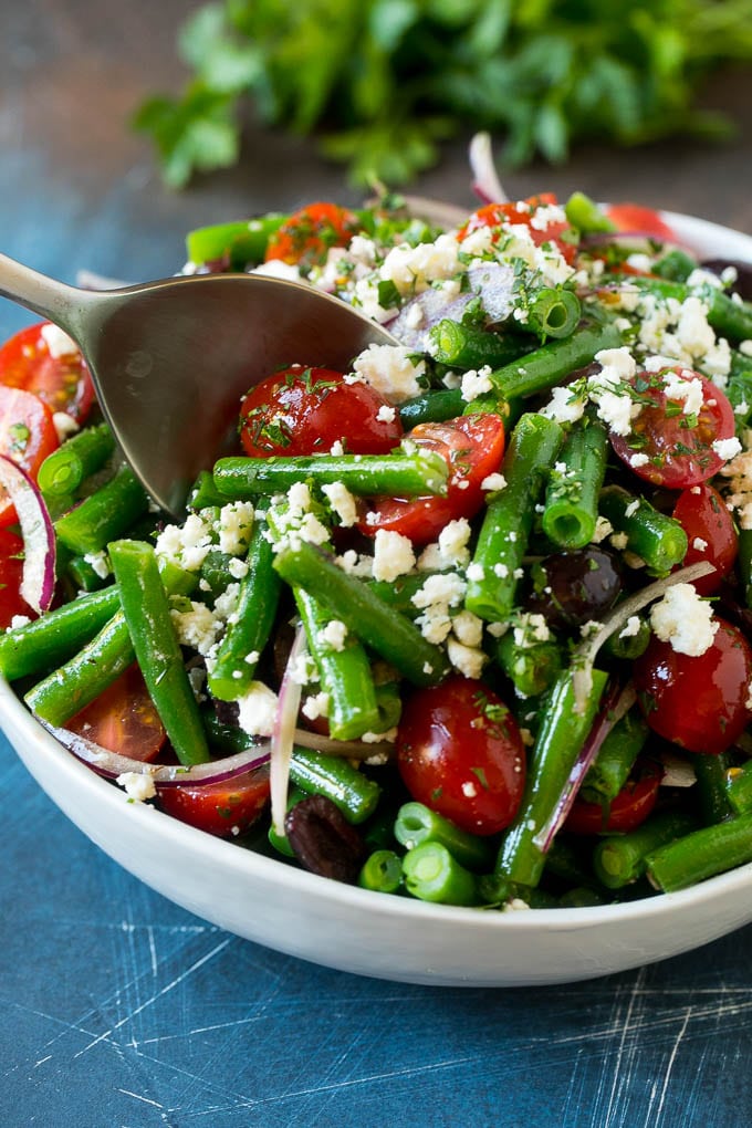 Green Bean Salad Recipe | String Bean Salad | Chopped Salad #greenbeans #tomatoes #olives #salad #cleaneating #lowcarb #glutenfree #sadud A serving spoon in a bowl of green bean salad.