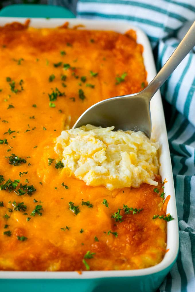 Hash Brown Casserole | Potato Casserole | Hash Brown Side Dish #potatoes #cheese #casserole #sidedish #sadud Hash brown casserole with potatoes, cheddar cheese, onions and sour cream, with a serving spoon in the dish.