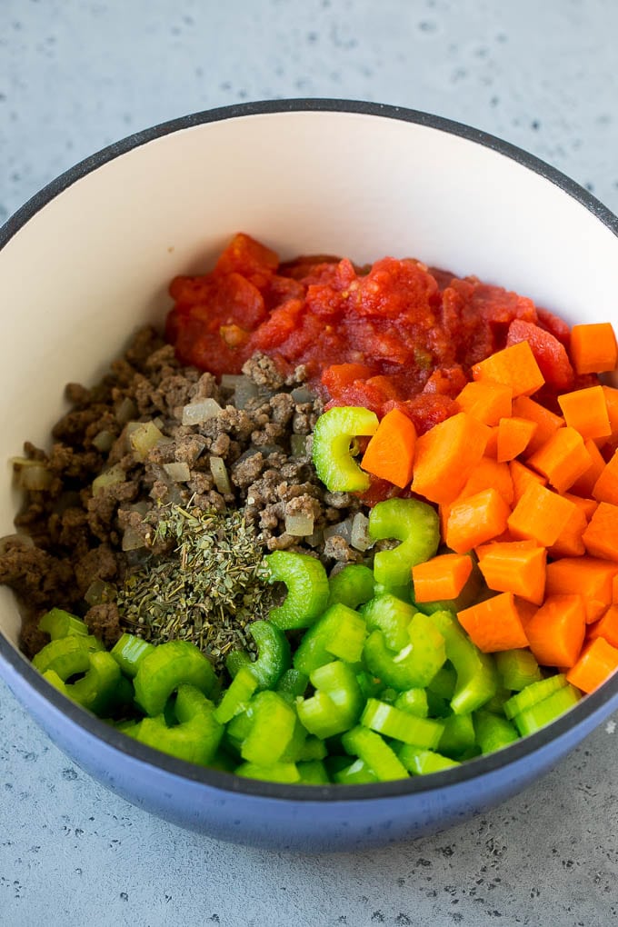 Ground beef, onions, tomatoes, carrots, celery, herbs and spices in a soup pot.