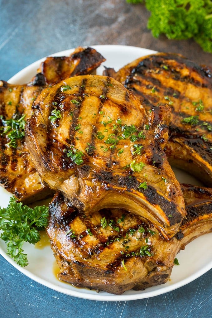 Pork Chop Marinade Recipe | Marinated Pork Chops | Grilled Pork Chops #pork #porkchops #grilling #dinner #sadud Pork chop marinade on grilled pork chops. The pork chops are on a serving plate garnished with parsley.