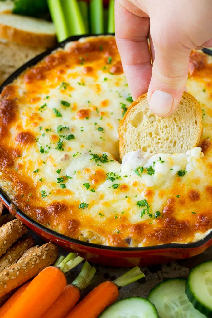 Reuben Dip Recipe | Corned Beef Dip | Cheese Dip #dip #cheese #cornedbeef #appetizer #lowcarb #keto #sadud A hand scooping out a serving of Reuben dip with baguette.