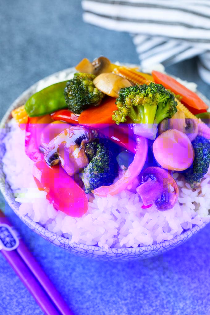 Vegetable stir fry served over rice in a bowl.