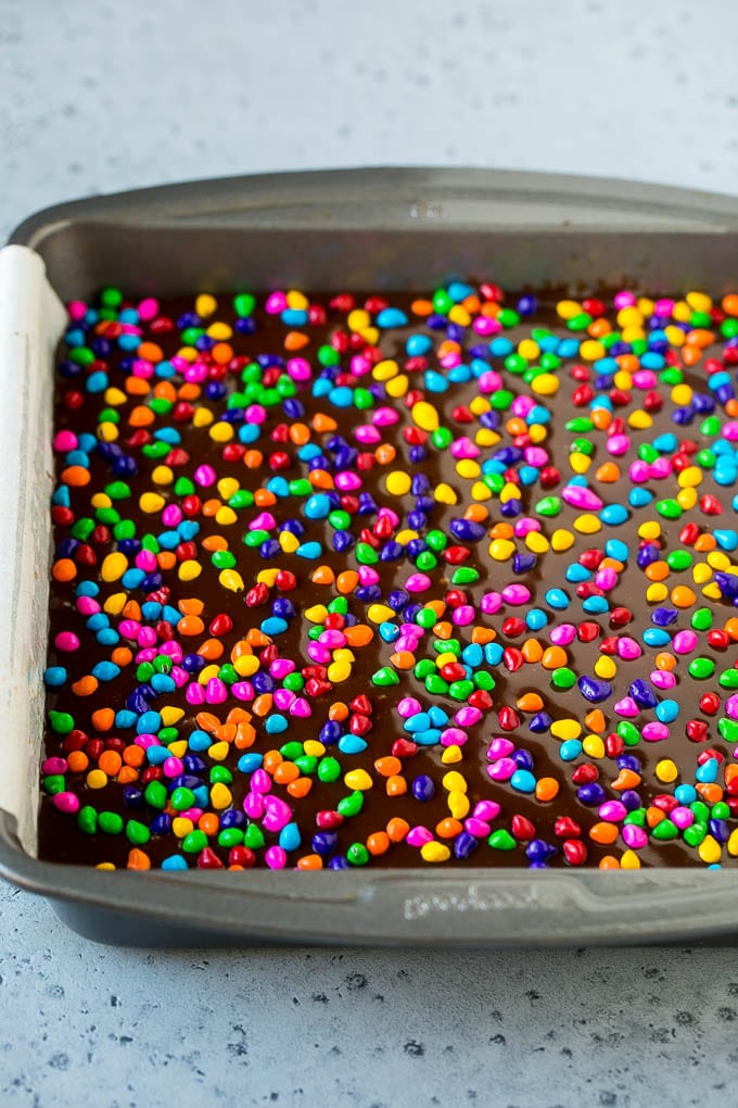 Cosmic Brownies Recipe | Cocoa Brownies | Frosted Brownies #brownies #chocolate #dessert #sadud #sprinkles A pan of cosmic brownies with rainbow sprinkles on top.