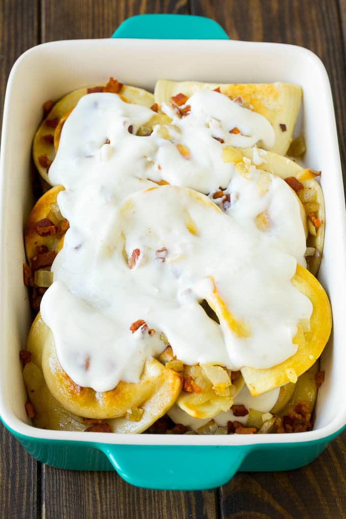 Pierogi Casserole Recipe | Potato Casserole #pierogis #casserole #bacon #cheddar #dinner #sadud Dumplings in a baking dish covered with creamy sauce.