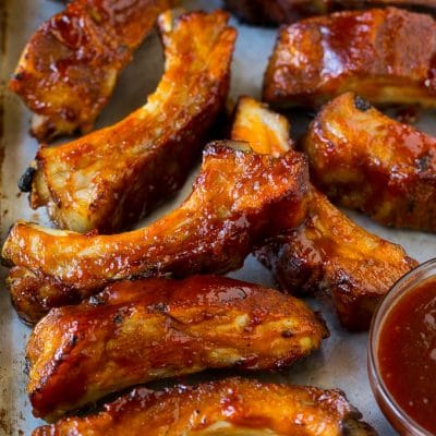Slow cooker ribs coated in BBQ sauce on a sheet pan.