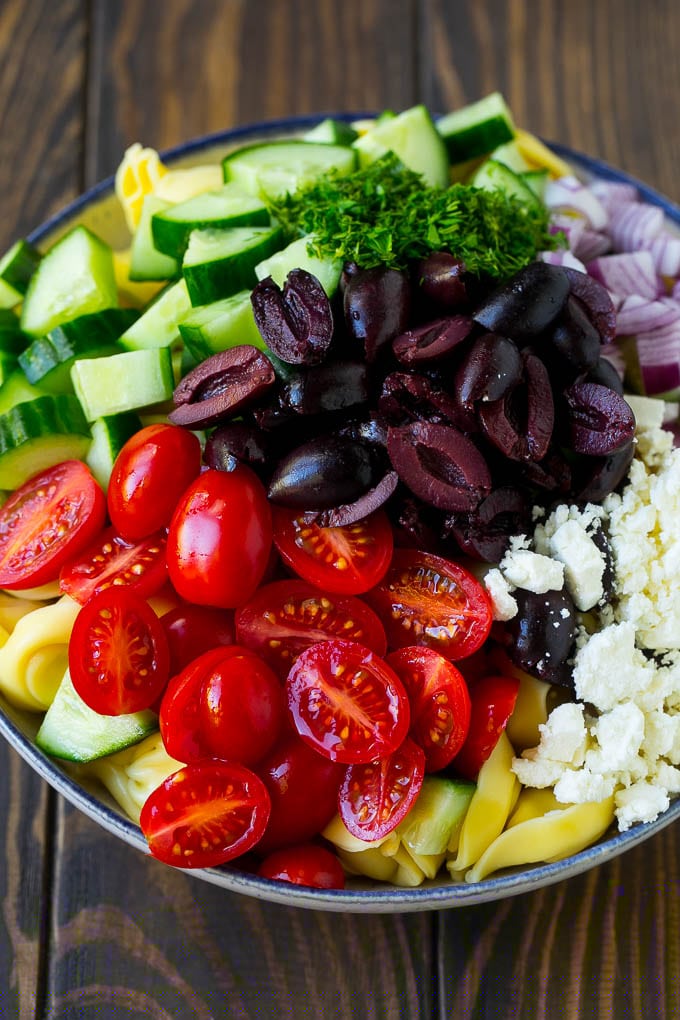 Greek Tortellini Salad Recipe | Pasta Salad | Tortellini Salad | Greek Salad #greek #tortellini #pasta #salad #cucumbers #olives #dinner #sadud Tortellini in a bowl topped with olives, tomatoes, cucumber and feta cheese.