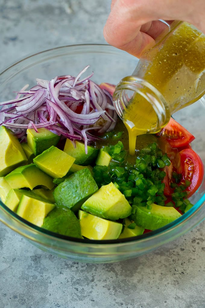 Tomato Avocado Salad Recipe | Avocado Salad | Tomato Salad #salad #tomato #avocado #glutenfree #cleaneating #dinner #sadud #healthy Dressing being poured over chopped veggies.