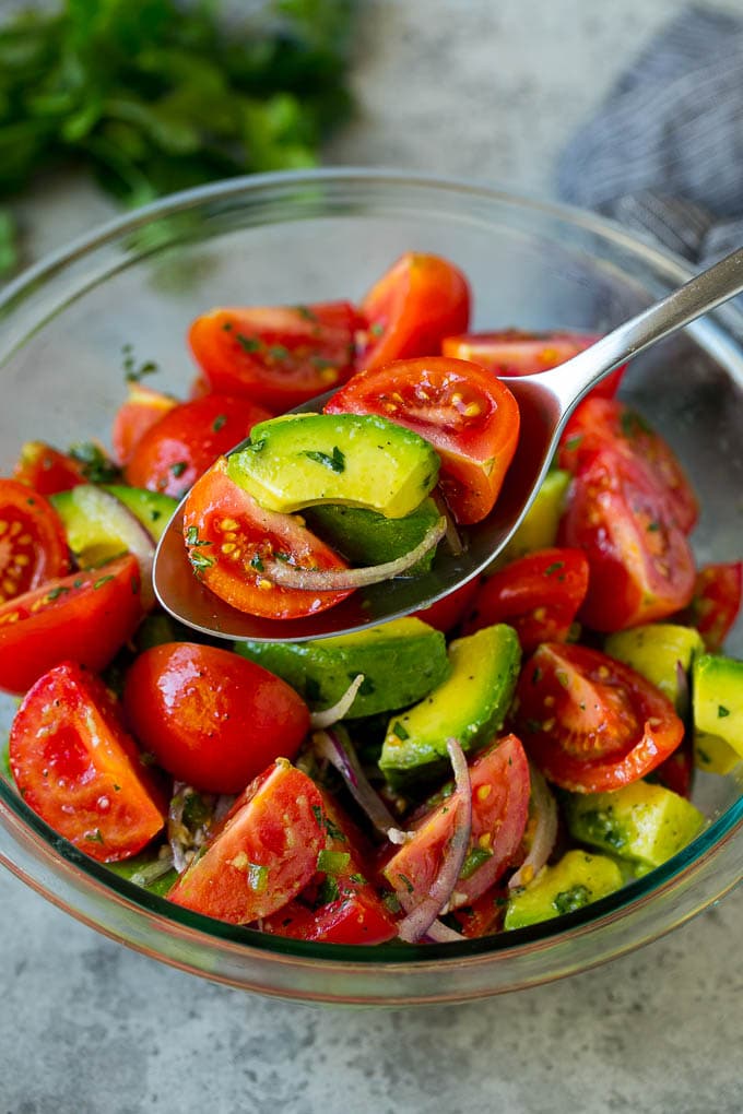 Tomato Avocado Salad Recipe | Avocado Salad | Tomato Salad #salad #tomato #avocado #glutenfree #cleaneating #dinner #sadud #healthy A serving spoon of veggies in a lime dressing.