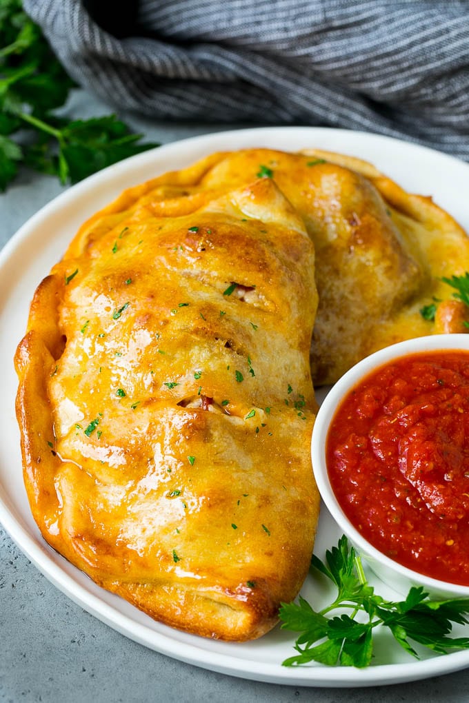 Calzone Recipe | Pizza Pockets #pizza #calzone #pepperoni #sausage #peppers #dinner #sadud #cheese A homemade calzone served with pizza sauce.