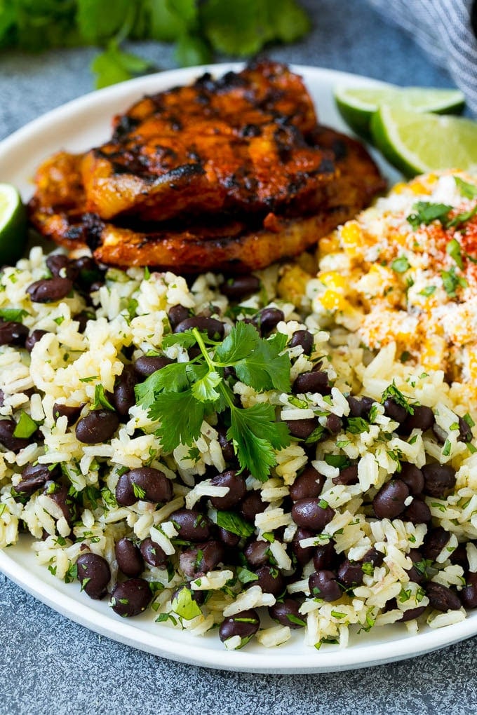 Black Beans and Rice Recipe | Cuban Black Beans | Beans and Rice #beans #rice #blackbeans #sidedish #glutenfree #dinner #sadud A plate of black beans and rice with grilled pork and Mexican corn.