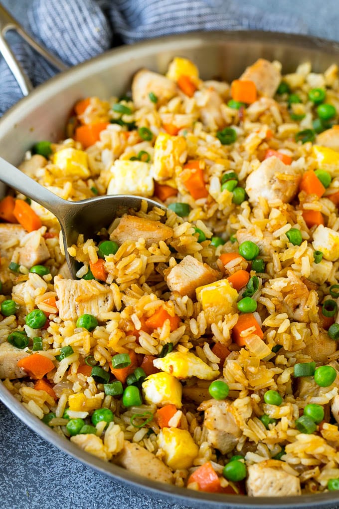 Chicken Fried Rice Recipe | Chinese Fried Rice #rice #chicken #peas #carrots #sidedish #dinner #sadud A serving spoon in a pan of chicken fried rice.