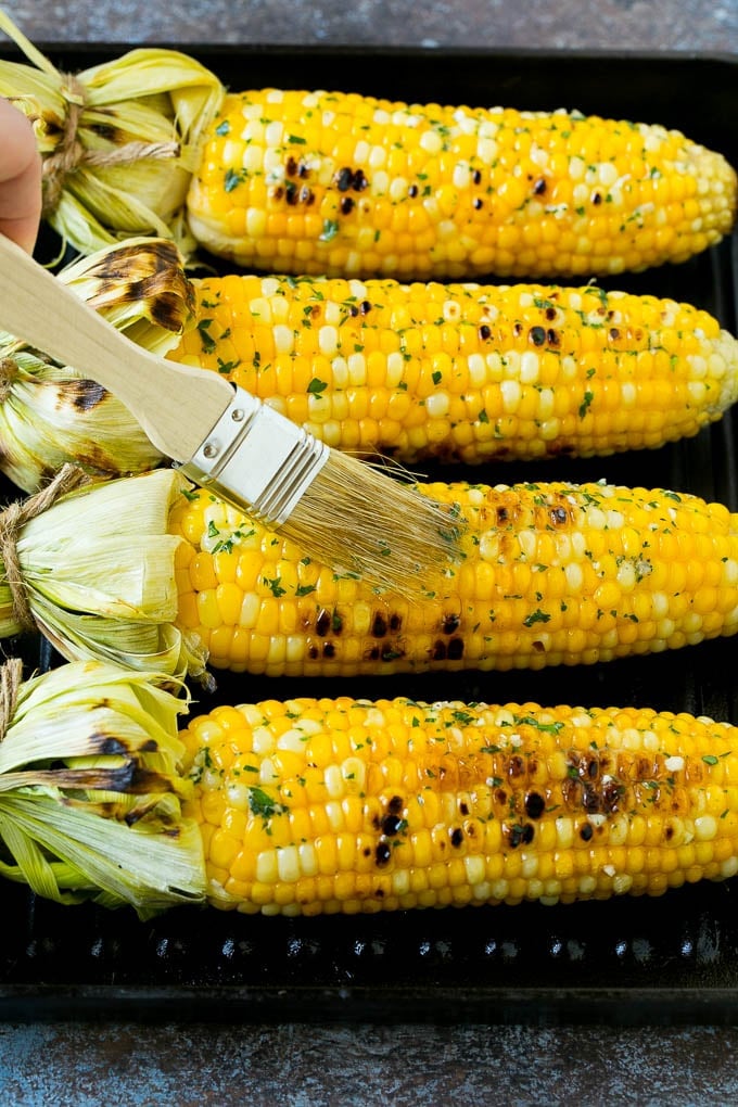 Grilled Corn on the Cob Recipe | Corn Recipe #corn #grilling #summer #sidedish #dinner #sadud Cobs being brushed with herb butter.