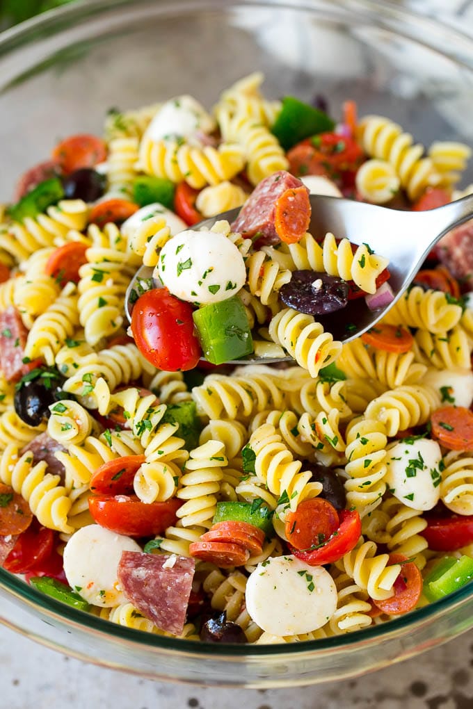 Italian Pasta Salad | Pasta Salad Recipe #pasta #salad #pastasalad #pepperoni #salami #olives #cheese #sidedish #sadud A serving spoon in a bowl of Italian style pasta salad.