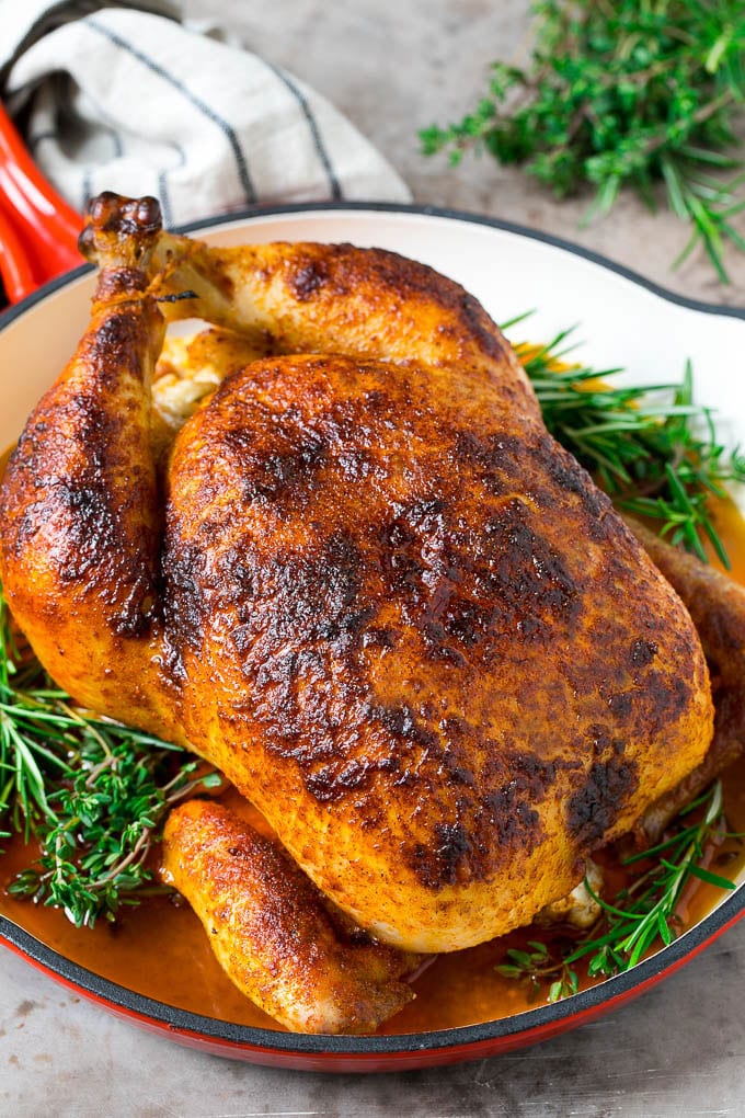 Rotisserie Chicken Recipe | Roasted Chicken #chicken #dinner #sadud #comfortfood A rotisserie chicken in a red skillet with sprigs of fresh herbs.