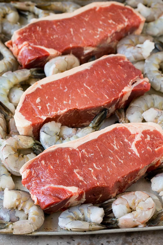 Surf and Turf Recipe | Seared Steak #steak #shrimp #keto #lowcarb #dinner #sadud Raw steaks and shrimp on a sheet pan.