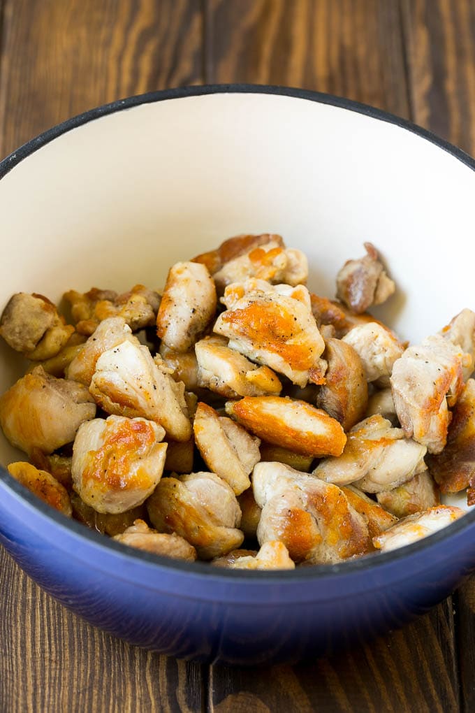 Seared chicken thigh pieces in a soup pot.