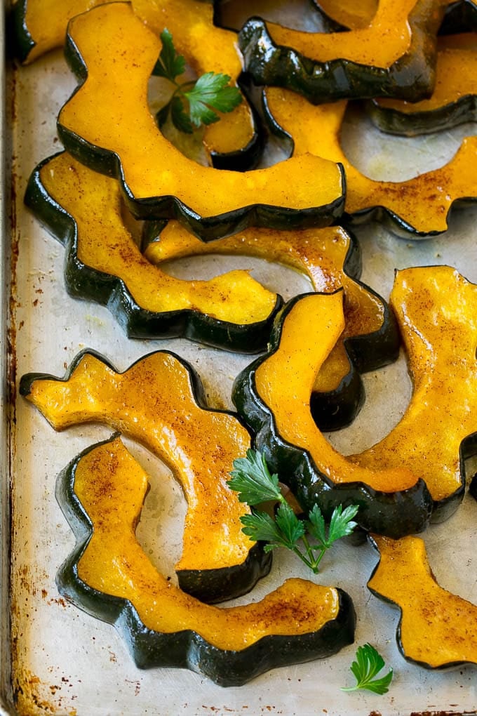 Roasted Acorn Squash | Acorn Squash Recipe #squash #winter #sidedish #dinner #sadud Sliced of cinnamon roasted acorn squash on a sheet pan.