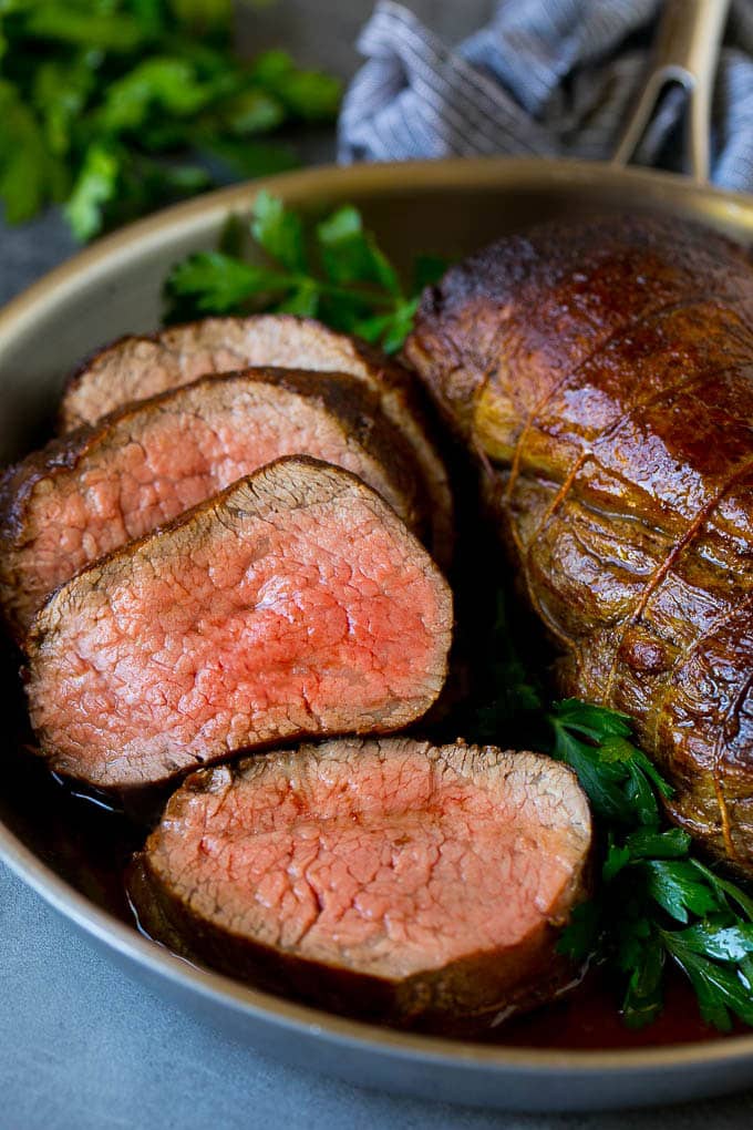 Beef Tenderloin with Garlic Butter #beef #steak #dinner #sadud A sliced beef tenderloin recipe in a pan, garnished with fresh parsley.