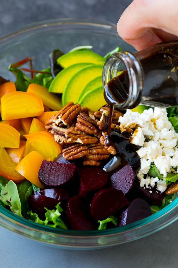 Beet Salad Recipe #beets #avocado #feta #salad #dinner #sadud Balsamic dressing being poured over beets, sliced avocado and feta cheese.