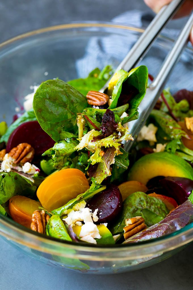 Beet Salad Recipe #beets #avocado #feta #salad #dinner #sadud Tongs serving a portion of beet salad tossed in balsamic dressing.