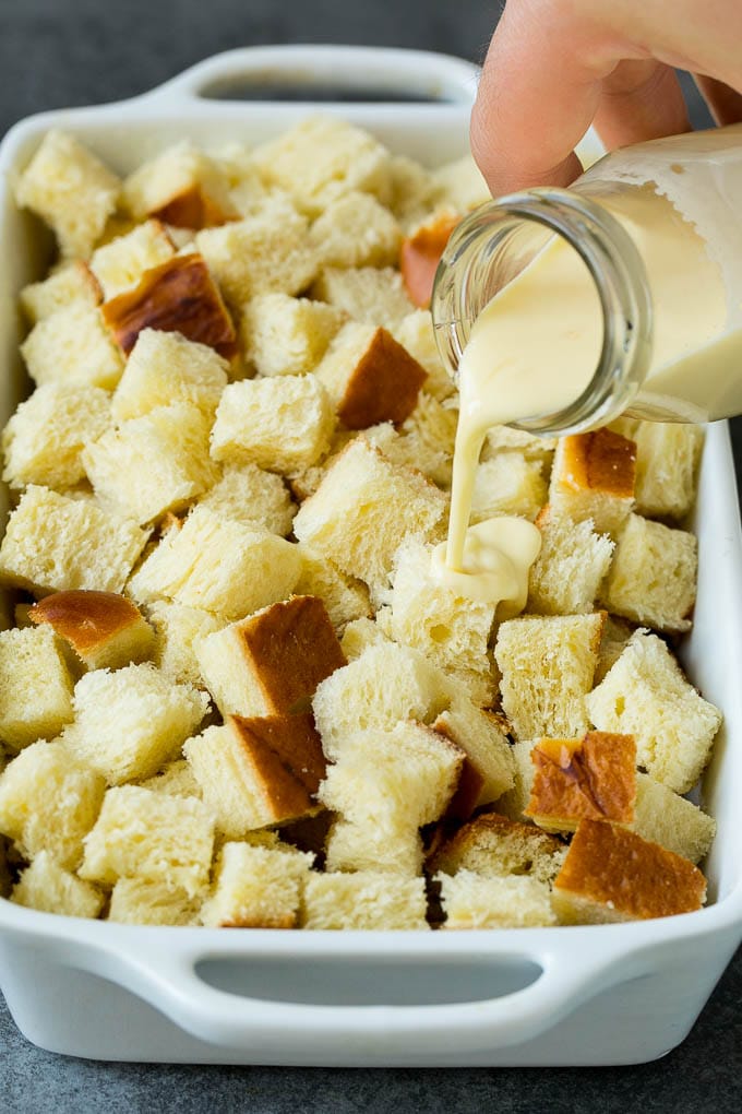 French Toast Casserole Recipe | French Toast Bake #frenchtoast #casserole #breakfast #brunch #sadud #bread A mixture of milk and eggs being poured over cubes of bread.