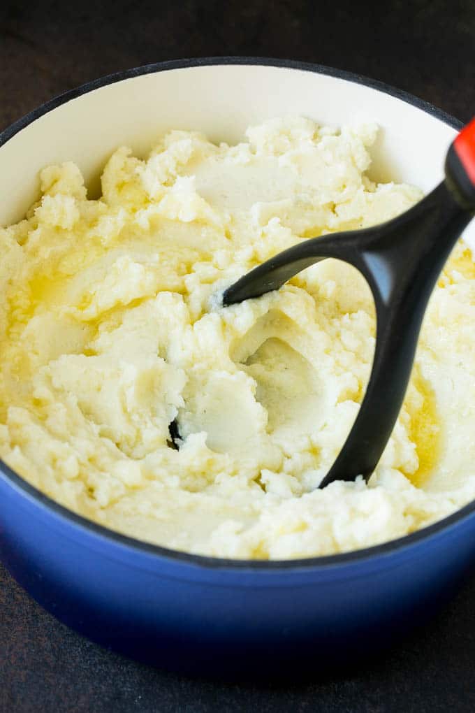 Garlic Mashed Potatoes Recipe #garlic #potatoes #mashedpotatoes #sidedish #dinner #thanksgiving #sadud A potato masher smashing diced cooked potatoes.