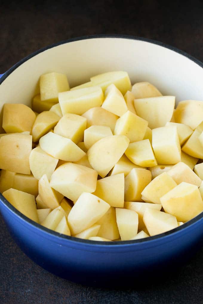 Garlic Mashed Potatoes Recipe #garlic #potatoes #mashedpotatoes #sidedish #dinner #thanksgiving #sadud Diced potatoes in a large blue pot.