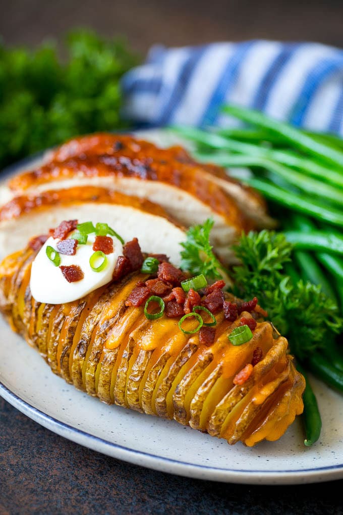 Hasselback Potatoes Recipe #potatoes #bacon #sidedish #cheese #dinner #sadud Hasselback potatoes on a plate, served with turkey and green beans.