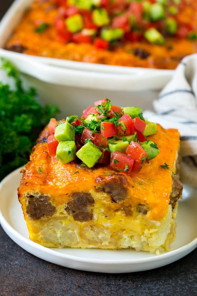 Sausage Egg Casserole Recipe | Egg Casserole #eggs #sausage #potato #cheese #casserole #breakfast #brunch #sadud A slice of sausage egg casserole with a garnish of fresh tomatoes.