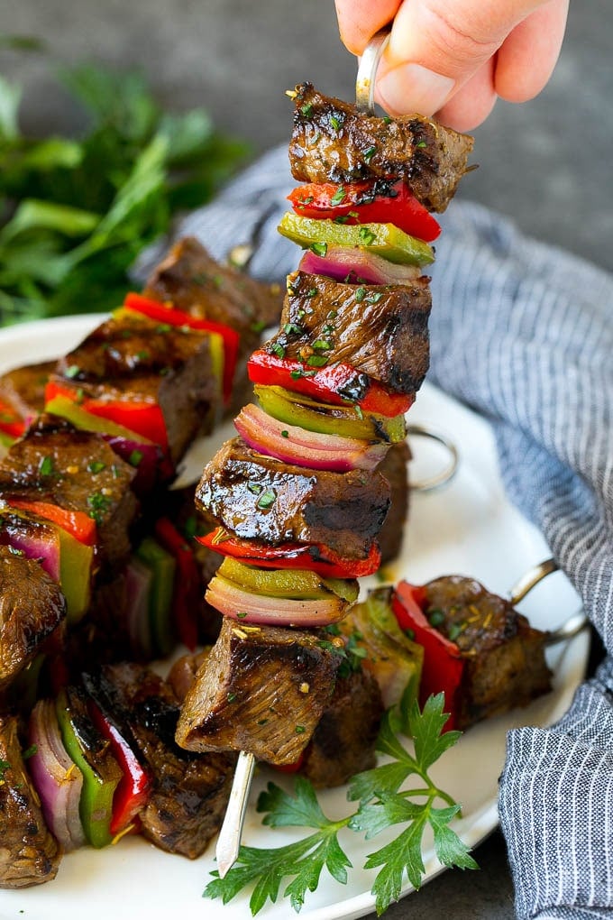Beef Shish Kabobs Recipe | Beef Kabobs #grilling #beef #steak #dinner #sadud #peppers A hand holding a beef shish kabob with peppers and onions.