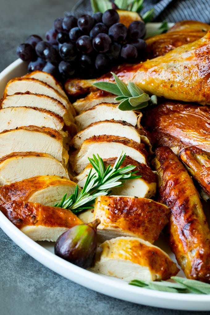 Spatchcock Turkey | Roasted Turkey | Thanksgiving Turkey #turkey #thanksgiving #dinner #fall #christmas #sadud Sliced spatchcock turkey on a serving platter garnished with herbs.