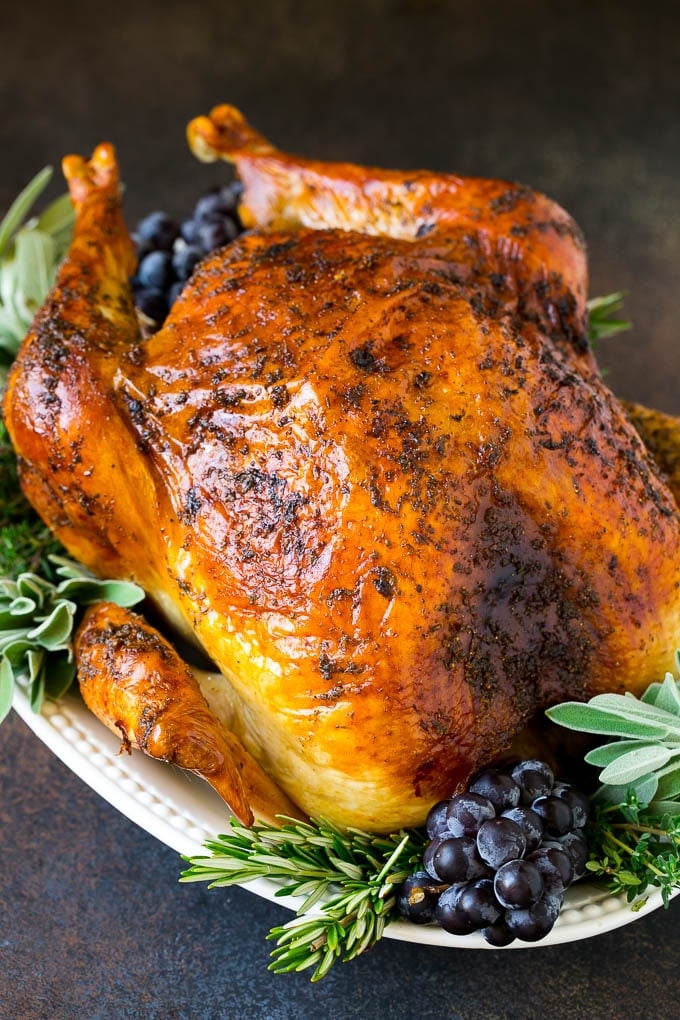 Thanksgiving Turkey Recipe | Roasted Turkey #turkey #thanksgiving #fall #dinner #sadud A whole roasted Thanksgiving turkey on a platter that's decorated with grapes and herbs.