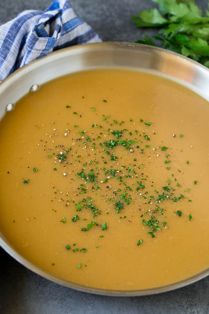 This is the best turkey gravy you'll ever have - it's smooth, creamy and full of savory flavors. Homemade gravy is a must have for any holiday meal, and my version is so simple to make. A pan of gravy topped with parsley and cracked pepper.