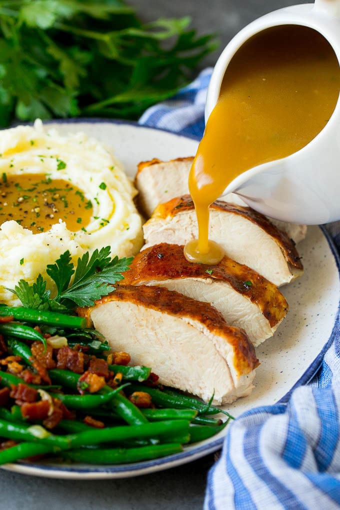 This is the best turkey gravy you'll ever have - it's smooth, creamy and full of savory flavors. Homemade gravy is a must have for any holiday meal, and my version is so simple to make. Turkey gravy being poured over sliced turkey breast.