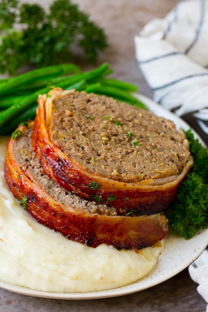 Bacon Wrapped Meatloaf Recipe | Beef Meatloaf #meatloaf #beef #groundbeef #bacon #dinner #sadud Slices of bacon wrapped meatloaf served over mashed potatoes with green beans.