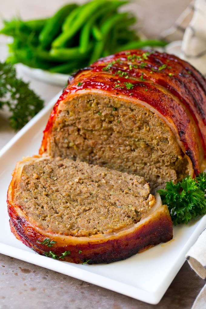 Bacon Wrapped Meatloaf Recipe | Beef Meatloaf #meatloaf #beef #groundbeef #bacon #dinner #sadud A bacon wrapped meatloaf with a slice out of it, on a serving platter.
