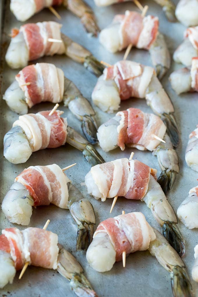 Bacon Wrapped Shrimp Recipe | Bacon Shrimp #shrimp #bacon #appetizer #dinner #sadud #seafood Raw seafood on a sheet pan wrapped in pork.