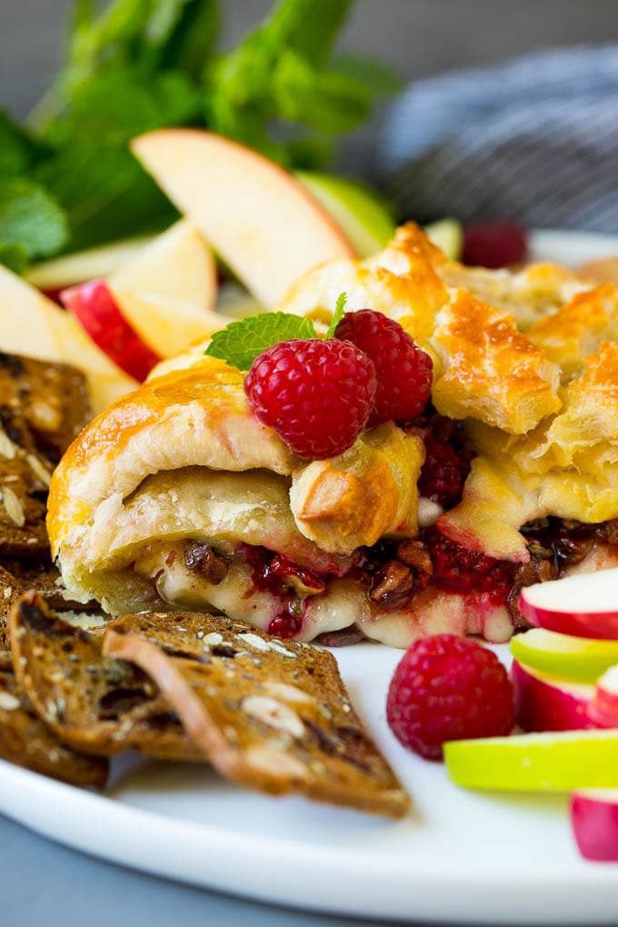 Baked Brie Recipe | Pastry Wrapped Brie #brie #cheese #appetizer #pecans #raspberries #sadud A cross section of baked brie filled with raspberries and pecans.