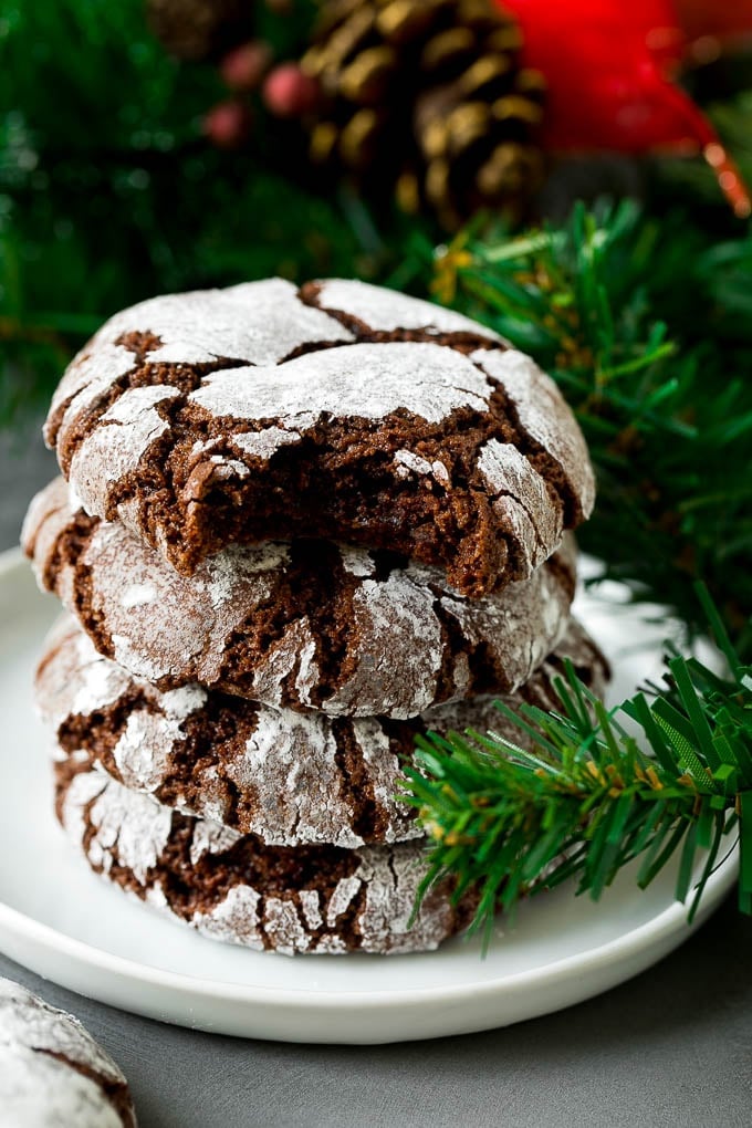 Chocolate Crinkle Cookies Recipe #cookies #chocolate #christmas #dessert #baking #sadud A stack of chocolate crinkle cookies with a bite taken out of one.