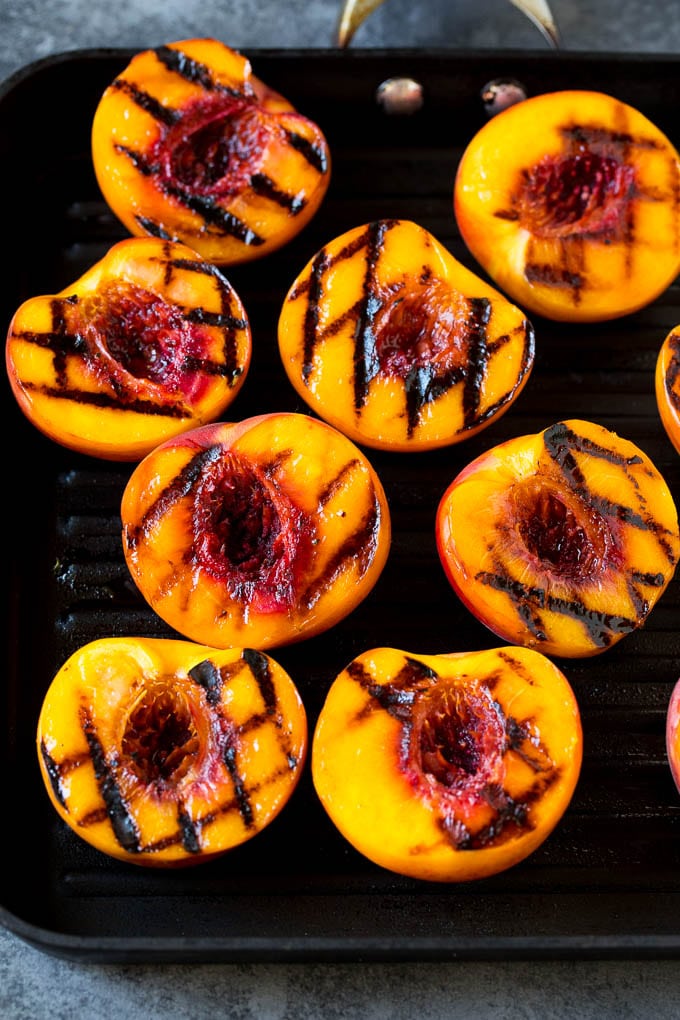 These grilled peaches are seared on the grill until tender and caramelized, then brushed with cinnamon honey for a sweet finish. Peach halves cooked on a grill pan.