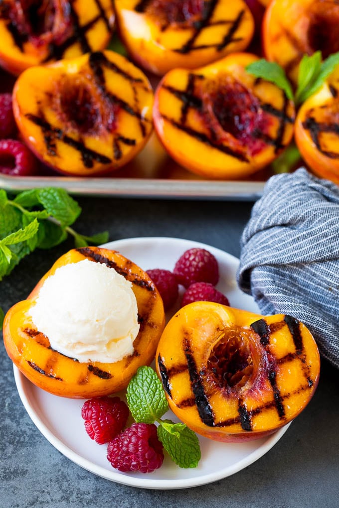 These grilled peaches are seared on the grill until tender and caramelized, then brushed with cinnamon honey for a sweet finish. Grilled peaches topped with a scoop of vanilla ice cream.