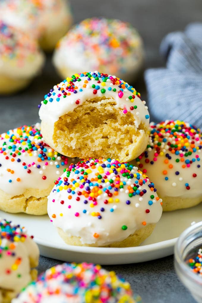 Italian Cookies Recipe | Almond Cookies #cookies #italianfood #frosting #sprinkles #baking #christmas #sadud A plate of Italian cookies with a bite taken out of one.