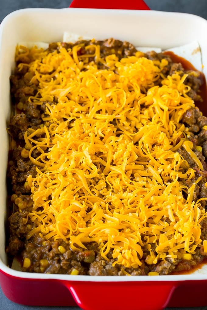 Mexican Lasagna Recipe | Mexican Casserole #mexican #lasagna #groundbeef #beans #dinner #cheese #sadud Layers of tortillas, ground beef and shredded cheese in a baking dish.