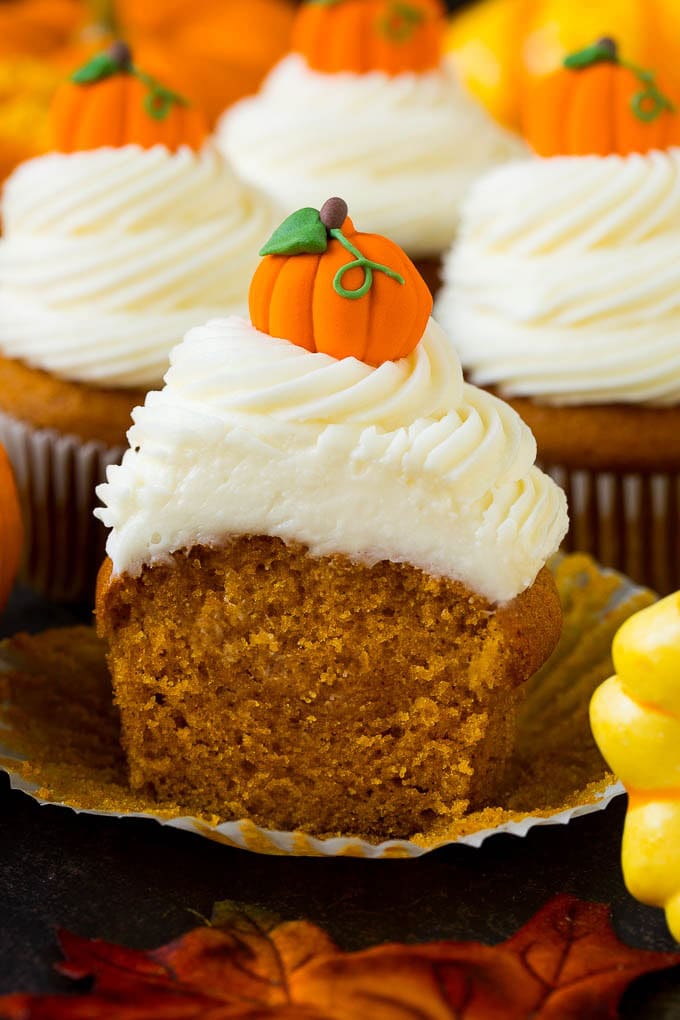 Pumpkin Cupcakes Recipe | Pumpkin Cake #cake #cupcakes #pumpkin #frosting #baking #fall #thanksgiving #sadud A pumpkin cupcake cut in half, surrounded by fall decorations.