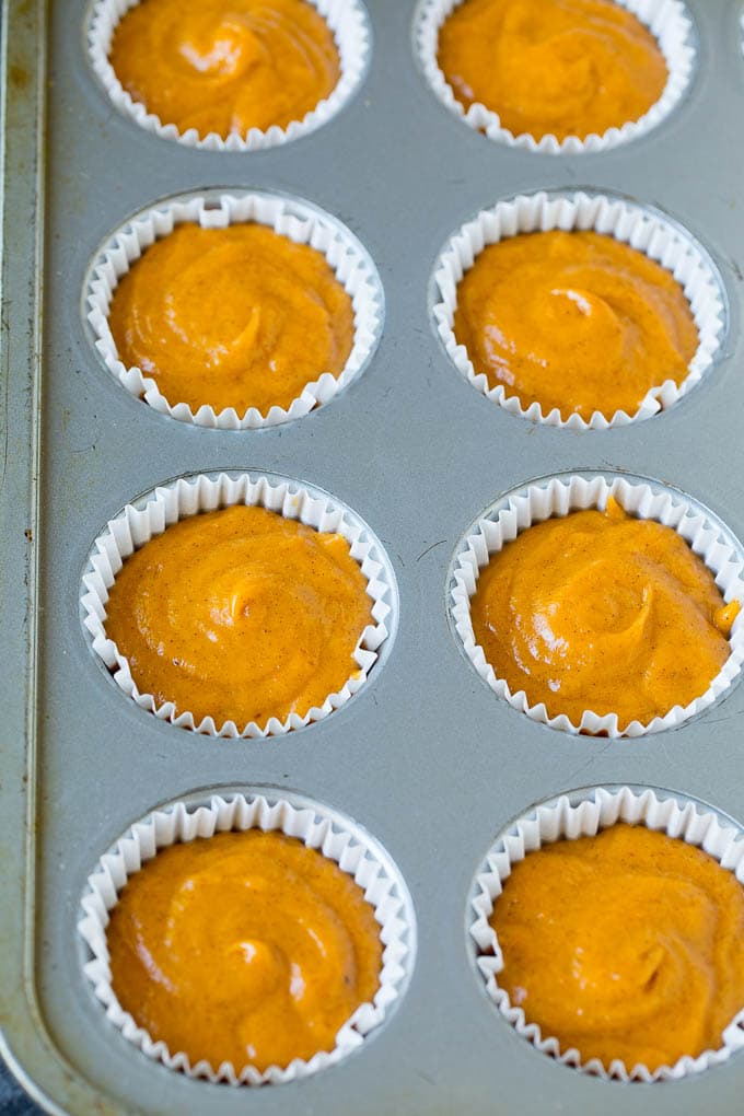 These pumpkin muffins are light and tender treats filled with plenty of pumpkin puree and spice, then topped with brown sugar streusel and baked to perfection. Pumpkin batter poured into a baking tin.
