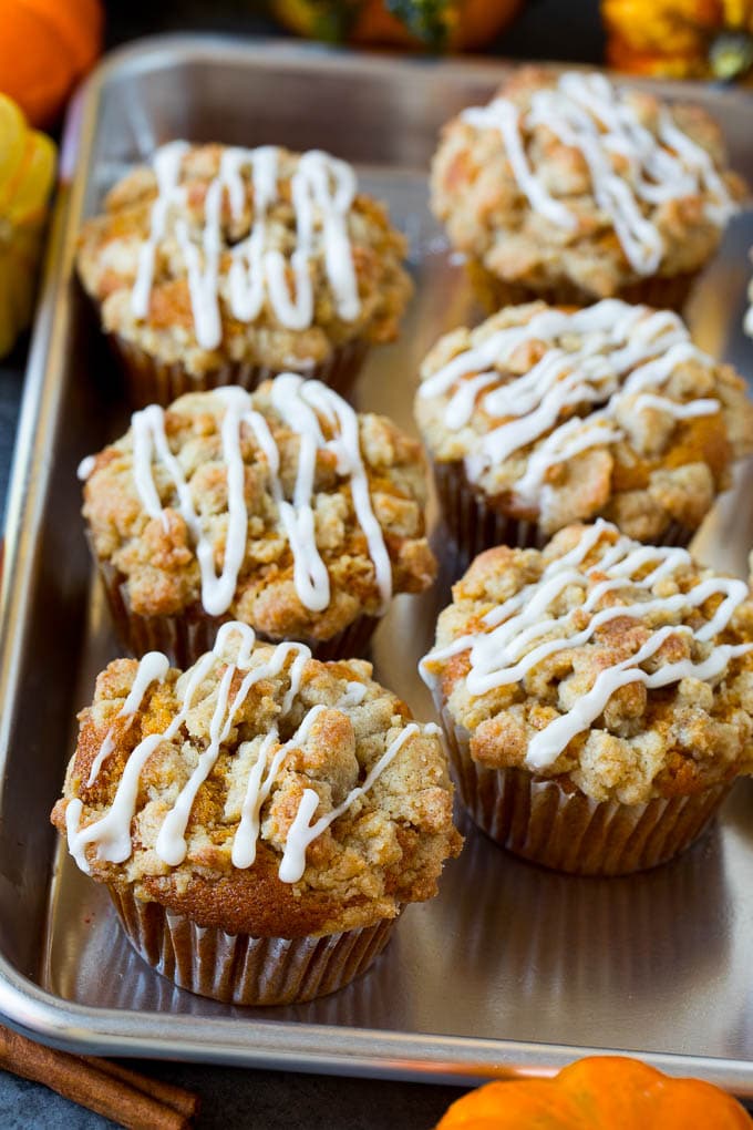 These pumpkin muffins are light and tender treats filled with plenty of pumpkin puree and spice, then topped with brown sugar streusel and baked to perfection. A tray of pumpkin muffins topped with glaze.
